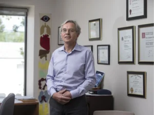 Dr. Peter, Chairperson of the Sanctum Care Group Board of Directors, standing in his office in front of his framed credentials